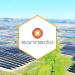 Aerial view of Sonnedix solar farm with extensive photovoltaic arrays and company logo overlay in mountainous landscape